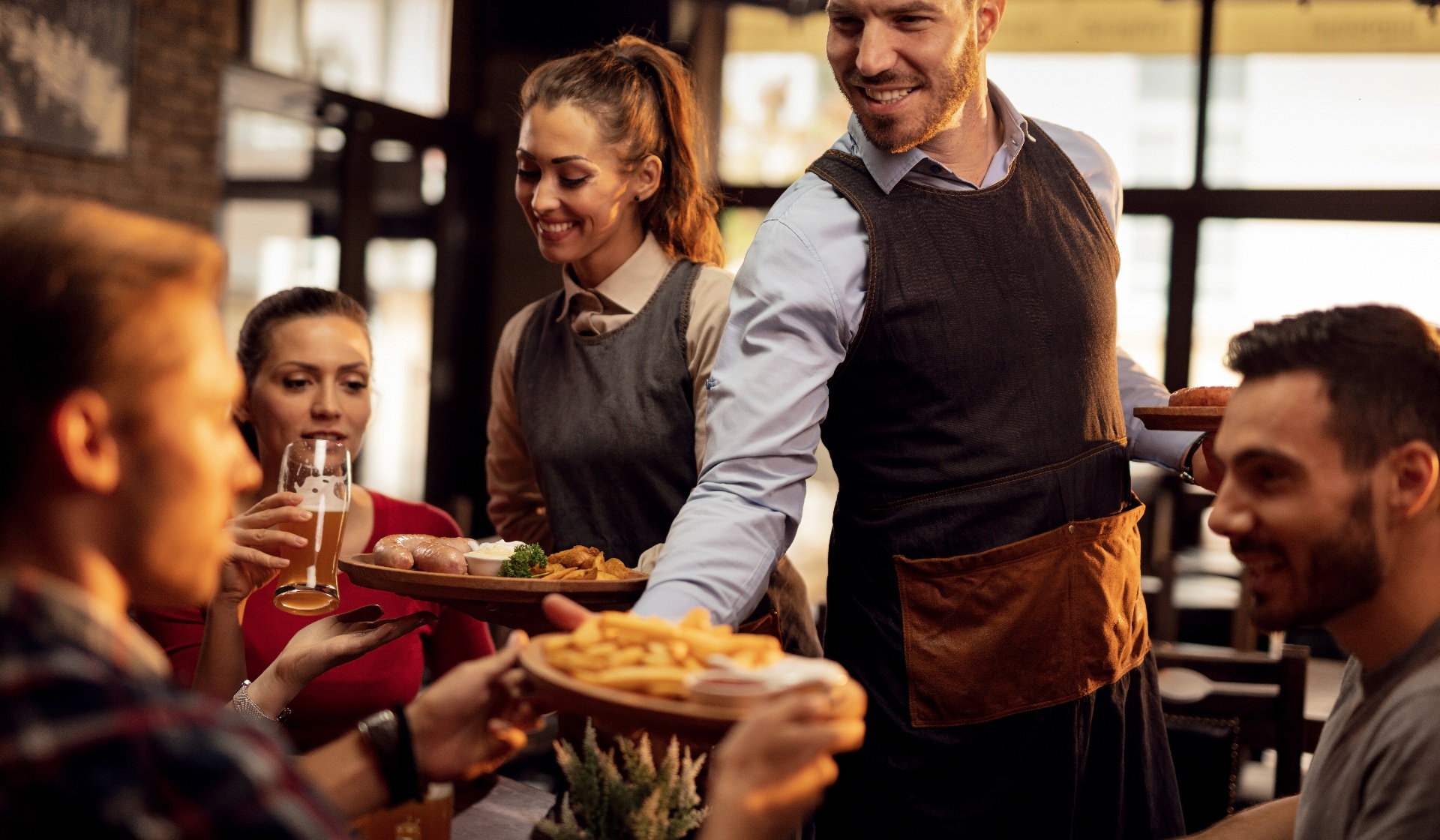 Young waiters serving lunch in busy restaurant